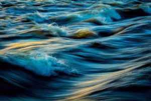 Rushing water with blue and golden reflections