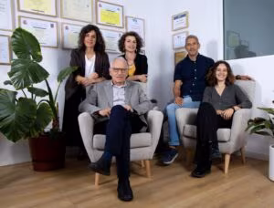Il team di Clínica Synaptica in poltrona nel suo studio di Barcellona davanti a una parete di diplomi