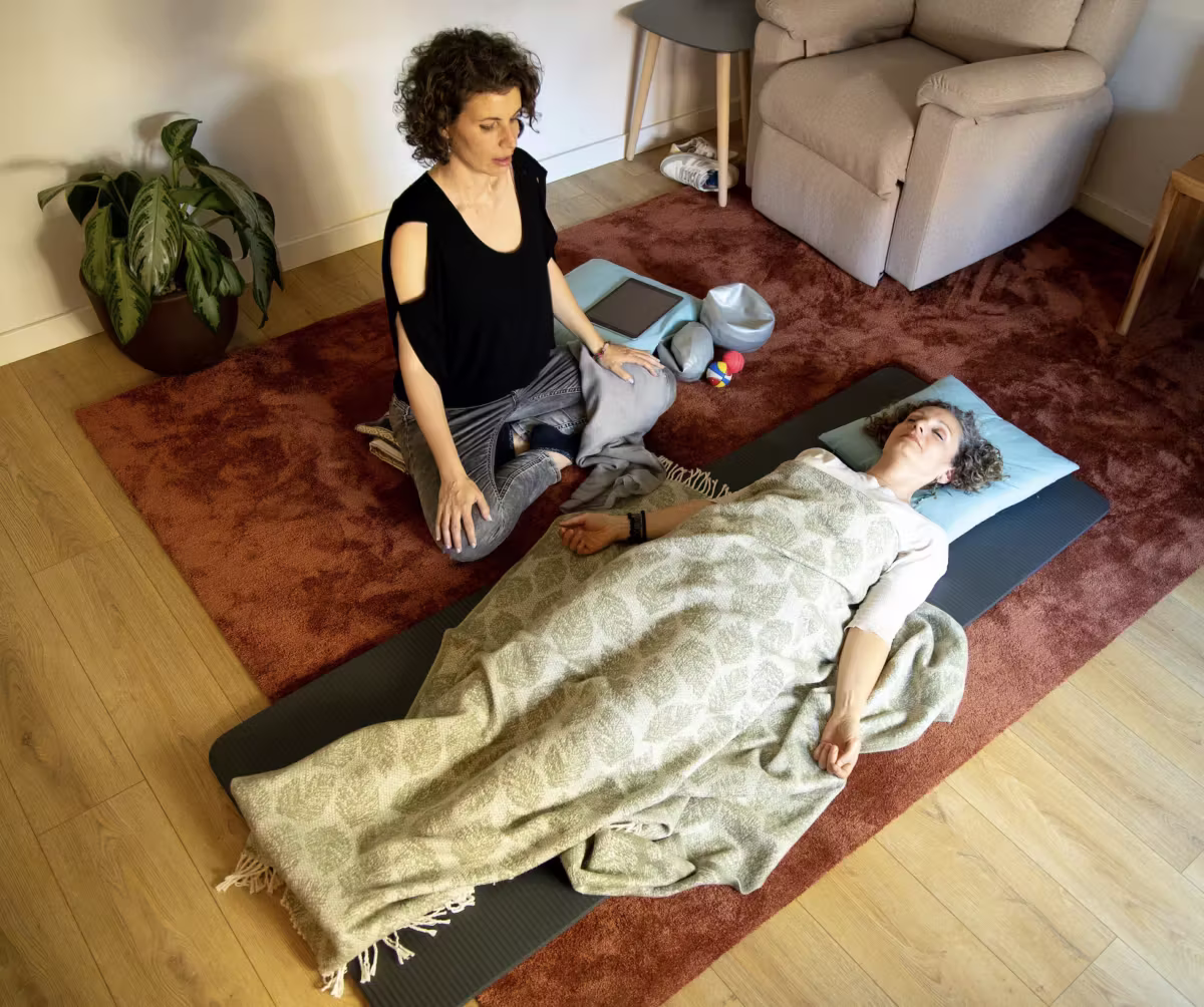 Terapeuta accompagna una donna sdraiata sotto una coperta in una sessione di TRE