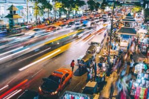 Busy street at night with moving traffic and street stalls