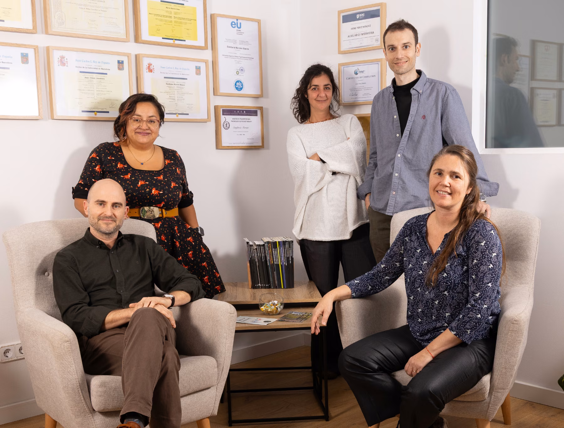 Equipo de Clínica Synaptica posando en la consulta ante diplomas enmarcados