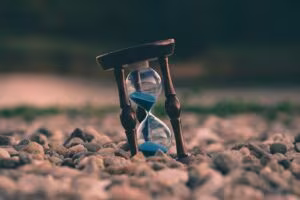 Hourglass with blue sand on a stone floor