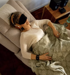 Reclining patient wearing an eye mask and headphones under a blanket